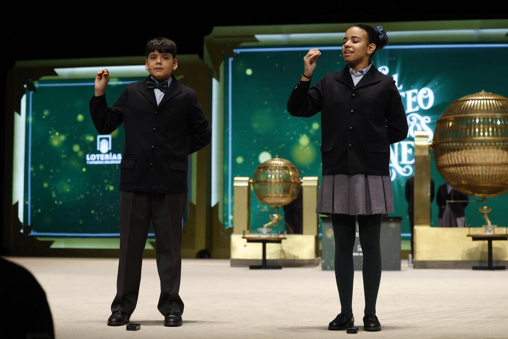 Yesica Paola Valencia Gómez y Francisco Moreno Durán se dirigen a la mesa mientras cantan el gordo que este año ha recaído en el número 88.008 durante el sorteo extraordinario de Navidad de la Lotería Nacional este viernes en el Teatro Real de Madrid